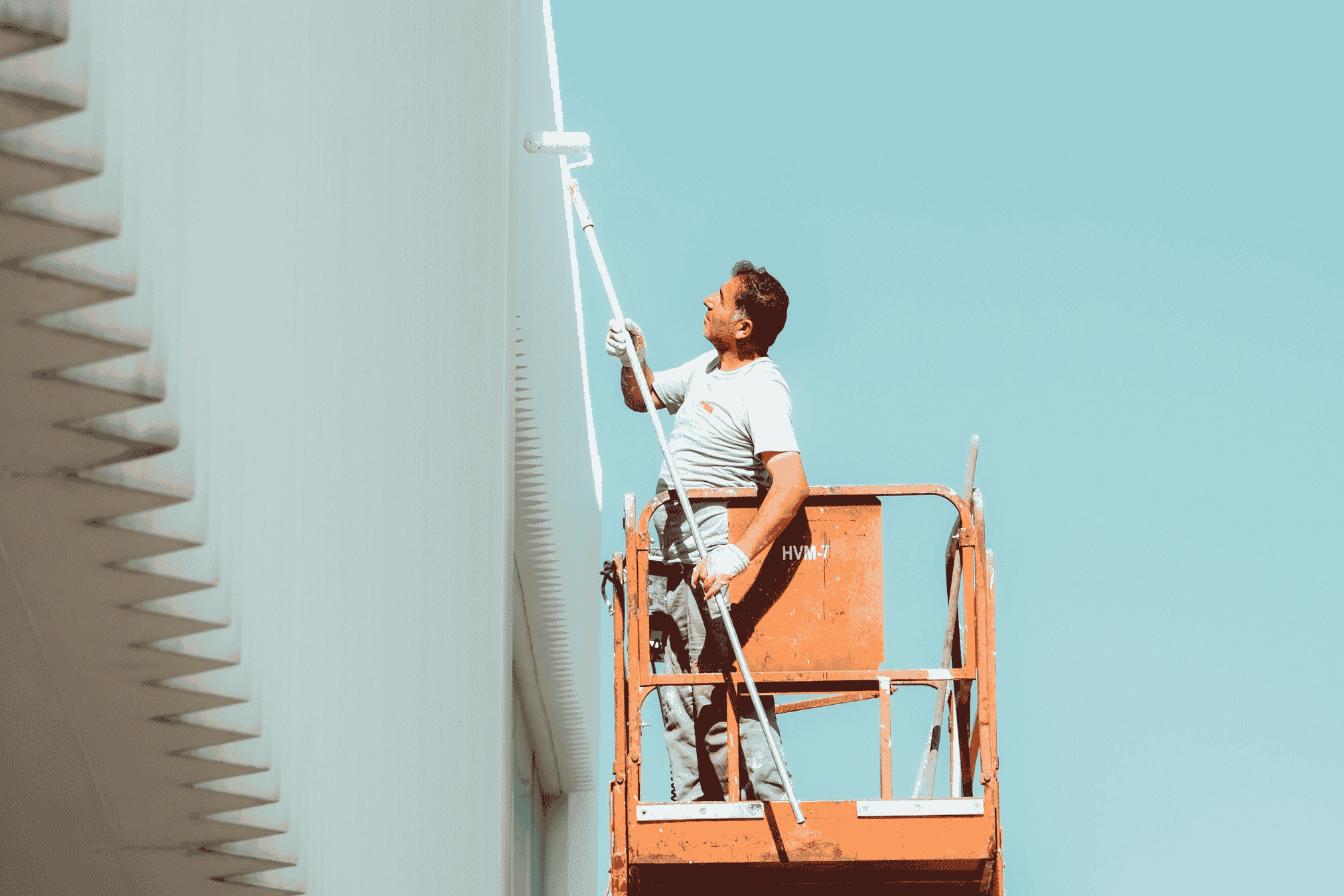 A painter on a lift applying fresh paint to a commercial building in Sydney, showcasing his skills at a height.