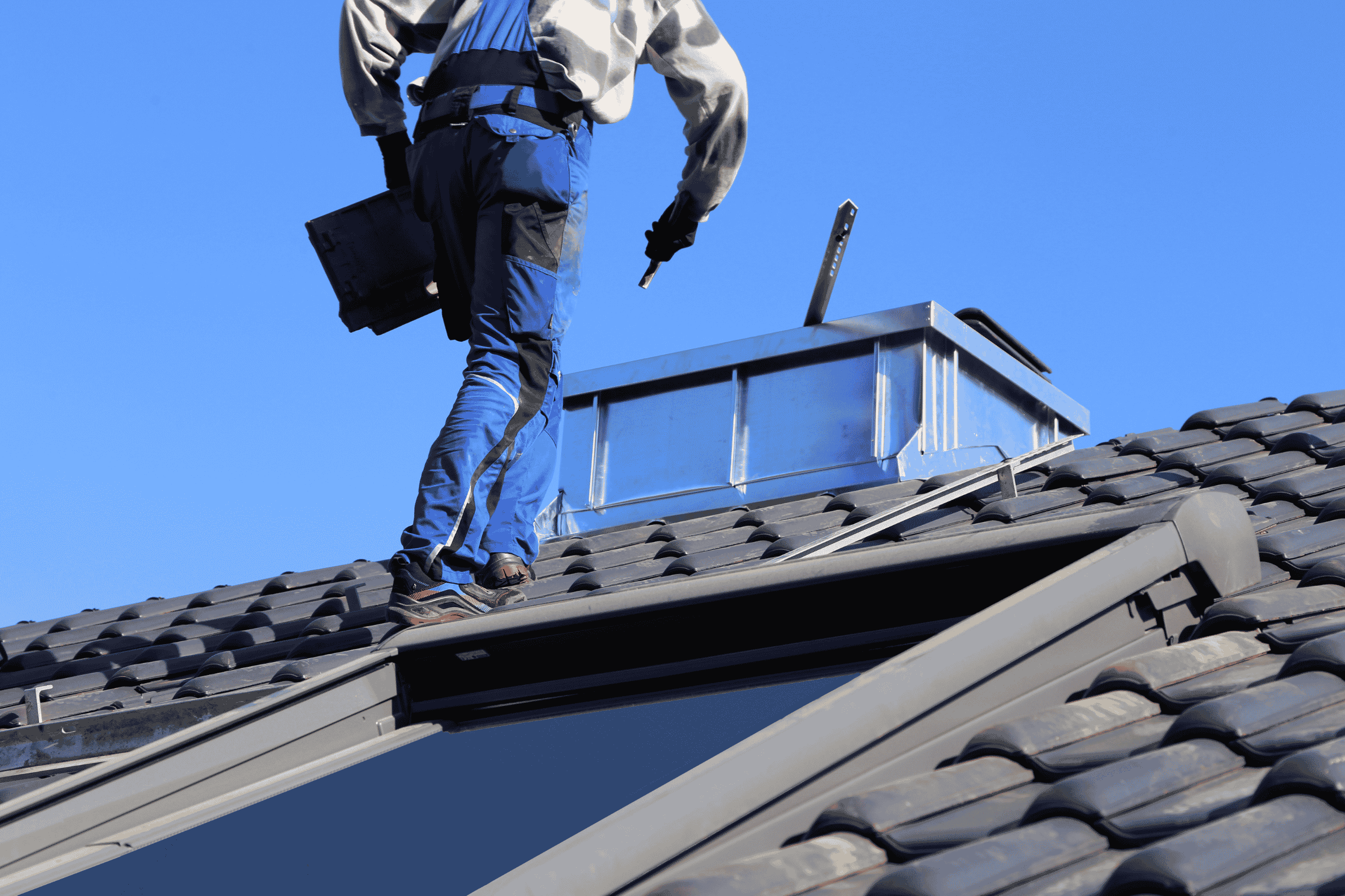 A man stands on a roof with a ladder, preparing for roof painting and restoration in Sydney.