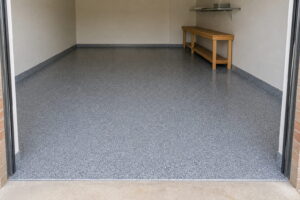 Finished flake epoxy garage floor in a Sydney home with a crisp edge at the roller door threshold and reflections along the slab